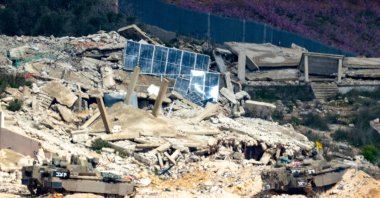 Israeli army fighting vehicles manoeuver across the border inside a destroyed Lebanese village as seen from the Upper Galilee in northern Israel, March 16, 2026. (AFP Photo)