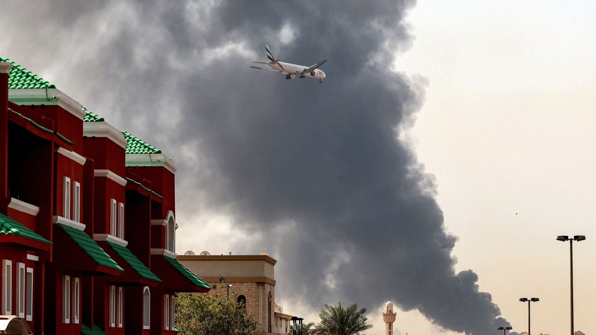 An Emirates aircraft prepares for landing as a smoke plume rises from an ongoing fire near Dubai International Airport, Dubai, UAE, March 16, 2026. (AFP Photo)