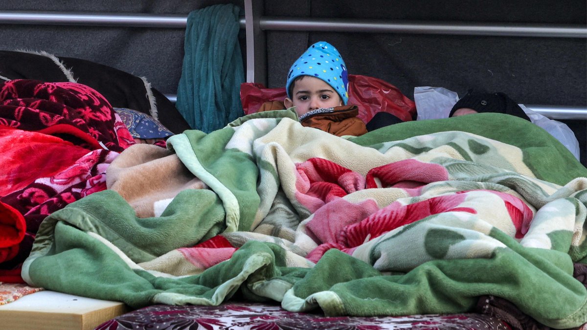 A boy looks on while lying under a blanket alongside family belongings in a makeshift encampment along the waterfront in Beirut, Lebanon, March 10, 2026. (AFP Photo)