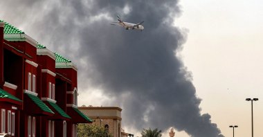 An Emirates aircraft prepares for landing as a smoke plume rises from an ongoing fire near Dubai International Airport, Dubai, UAE, March 16, 2026. (AFP Photo)