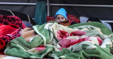 A boy looks on while lying under a blanket alongside family belongings in a makeshift encampment along the waterfront in Beirut, Lebanon, March 10, 2026. (AFP Photo)