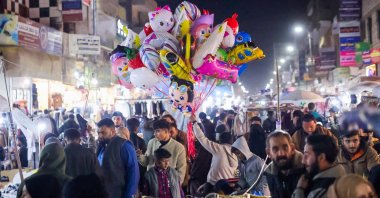 A seller displays balloons as people shop at a market, Raqqa, Syria, April 11, 2025. (AA Photo)