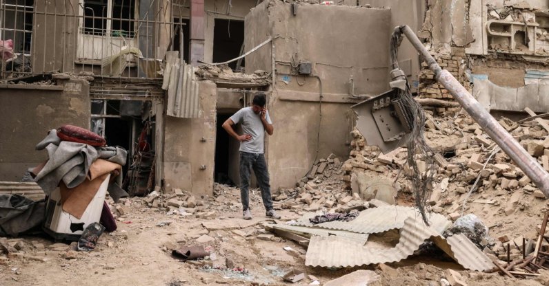 A man speaks on a mobile phone as he stands outside homes damaged by U.S.-Israeli military strikes on the Iranian capital Tehran, Iran, March 15, 2026. (AFP Photo)