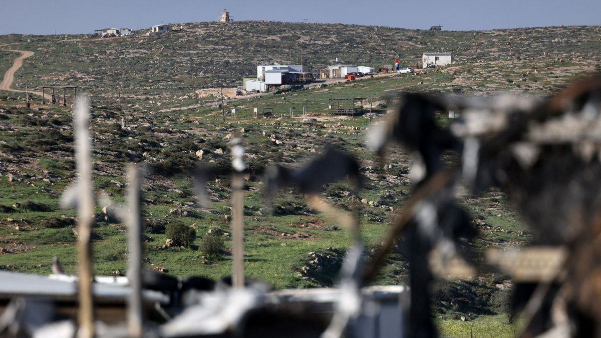 An Israeli outpost is pictured through a burnt lorry that was set on fire by illegal Israeli settlers from a nearby settlement, in Susya village, south of Hebron in the Israeli-occupied West Bank, Palestine, Feb. 25, 2026. (AFP Photo)