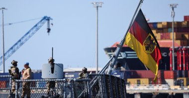 Military personnel stand next to a German flag with a coat of arms, on board the German frigate FGS Nordrhein-Westfalen as it arrives at the port of Limassol, amid the conflict in the Middle East, Limassol, Greek Cyprus, March 8, 2026. (Reuters Photo)