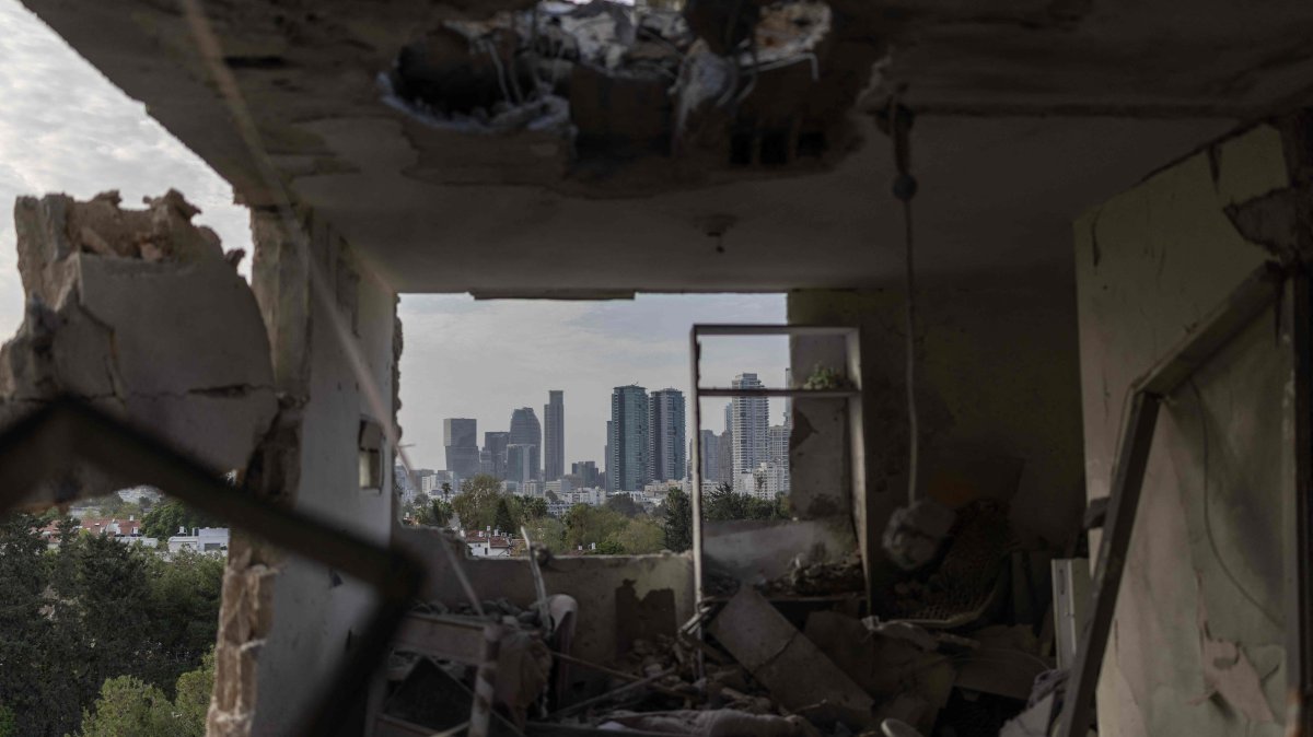 This photograph shows the interior of a destroyed apartment, with the Tel Aviv skyline visible in the background, following an overnight Iranian missile strike, Israel, March 19, 2026. (AFP Photo)