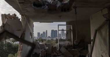 This photograph shows the interior of a destroyed apartment, with the Tel Aviv skyline visible in the background, following an overnight Iranian missile strike, Israel, March 19, 2026. (AFP Photo)