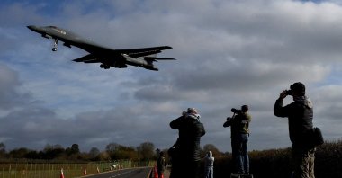 People use their cameras as a USAF B-1 bomber approaches to land at RAF Fairford airbase, used by United States Air Force (USAF) personnel, amid the U.S.-Israeli conflict with Iran, Fairford, U.K., March 17, 2026. (Reuters Photo)