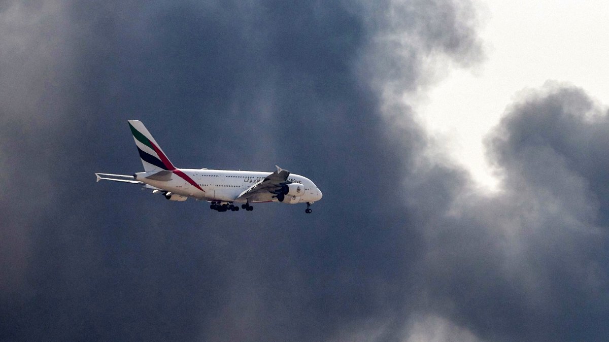An Emirates Airbus A380 aircraft prepares for landing as a smoke plume rises from an ongoing fire near Dubai International Airport in Dubai, March 16, 2026. (AFP Photo)