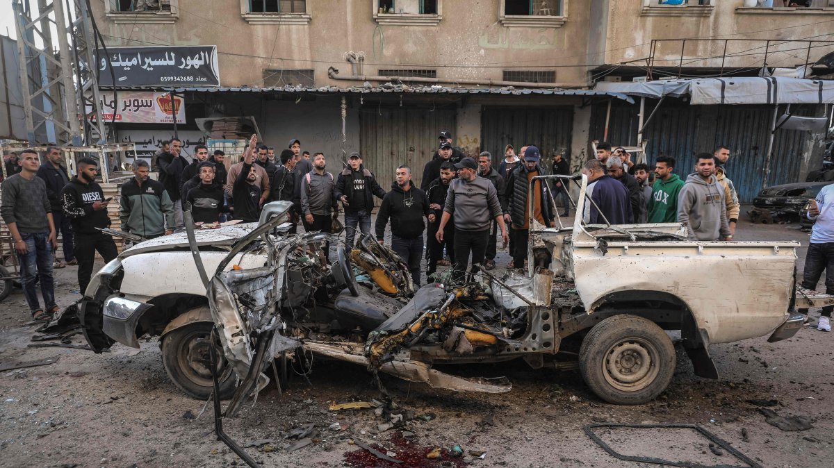 Men gather around a destroyed Palestinian police jeep that was targeted by an Israeli air strike in Nuseirat refugee camp in the central Gaza Strip, March 22, 2026. (AFP Photo)