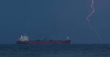 The tanker RARITY sits at anchor as lightning flashes in the distance, amid the U.S.-Israeli conflict with Iran, off Sultan Qaboos Port, Muscat, Oman, March 21, 2026. (Reuters Photo)