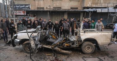 Men gather around a destroyed Palestinian police jeep that was targeted by an Israeli air strike in Nuseirat refugee camp in the central Gaza Strip, March 22, 2026. (AFP Photo)