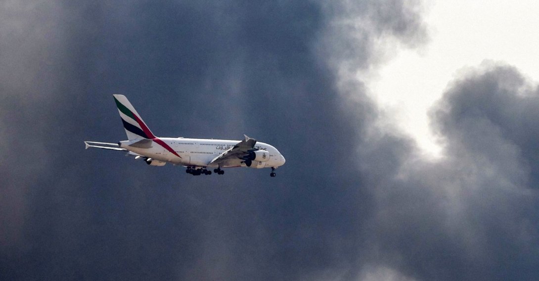 An Emirates Airbus A380 aircraft prepares for landing as a smoke plume rises from an ongoing fire near Dubai International Airport in Dubai, March 16, 2026. (AFP Photo)