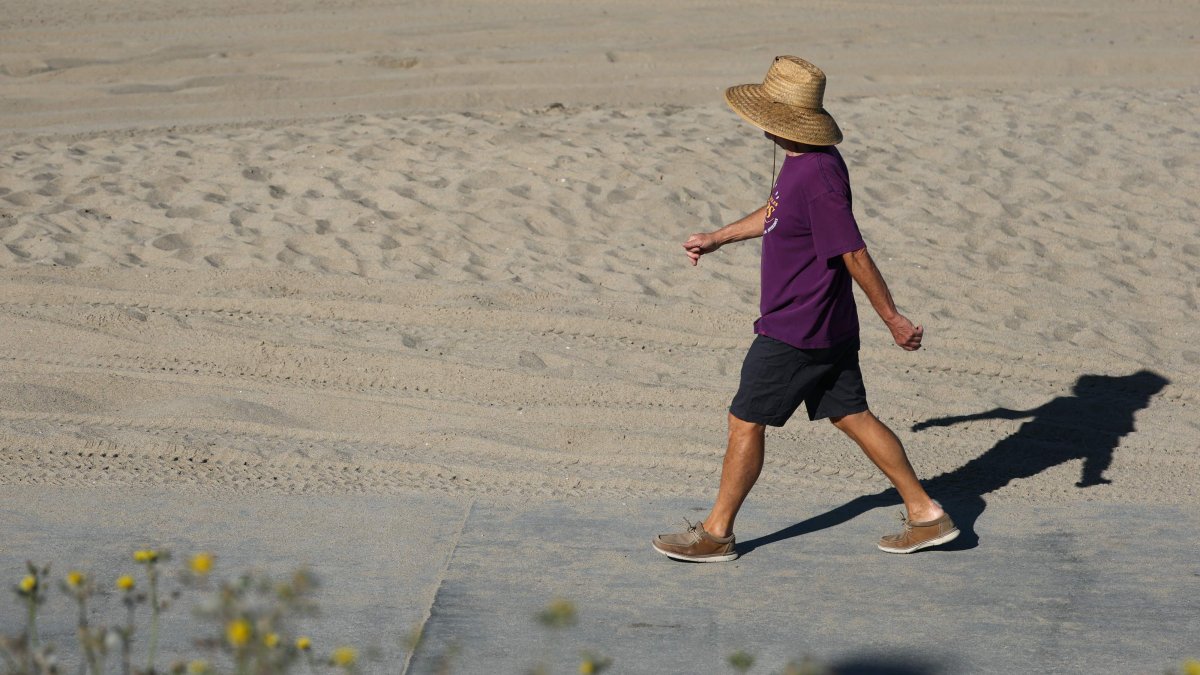 A person wears a hat for shade under the morning sun while walking along The Strand in Redondo Beach, California, U.S., March 20, 2026. (AFP Photo)