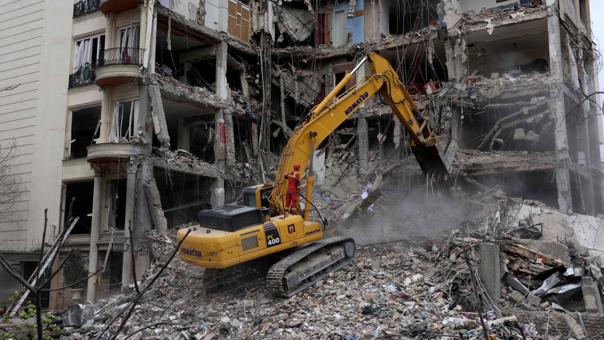 Iranian firefighters use an excavator to clear rubble from a residential building destroyed by an Israeli airstrike, Tehran, Iran, March 23, 2026. (AFP Photo)