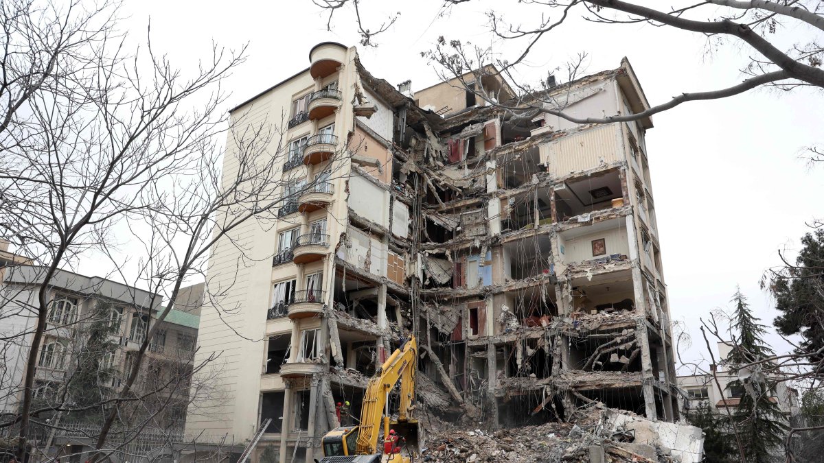 Iranian firefighters with the help of an excavator clear rubble from a destroyed residential building in northern Tehran, Iran, March 23, 2026. (AFP Photo) 