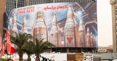 People on motorcycles ride past a large billboard with images of Iranian missiles, Tehran, Iran, March 15, 2026. (Reuters Photo)
