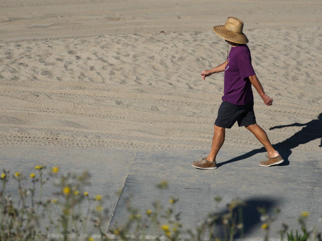 A person wears a hat for shade under the morning sun while walking along The Strand in Redondo Beach, California, U.S., March 20, 2026. (AFP Photo)