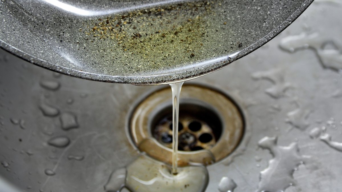 Used oil is poured into a kitchen sink. (Shutterstock Photo)