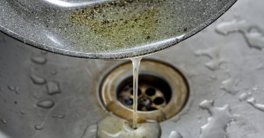 Used oil is poured into a kitchen sink. (Shutterstock Photo)