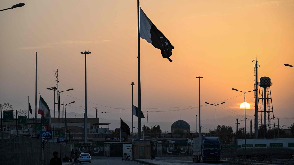 An Iranian national flag (L) flies at half-mast as Pakistan's flag (C) flutters during sunset at the Pakistan-Iran border crossing, Taftan, Balochistan province, Pakistan, March 4, 2026. (AFP Photo)