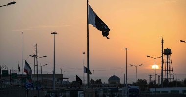 An Iranian national flag (L) flies at half-mast as Pakistan's flag (C) flutters during sunset at the Pakistan-Iran border crossing, Taftan, Balochistan province, Pakistan, March 4, 2026. (AFP Photo)
