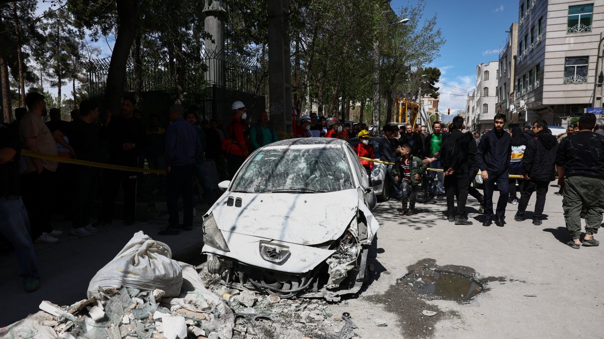 People gather near a damaged car at the site of a residential building damaged by a strike, amid the U.S.-Israeli conflict with Iran, in Tehran, Iran, March 27, 2026. (Reuters Photo)