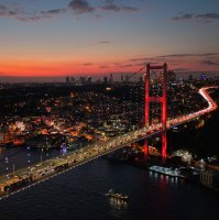 The Bosporus Bridge glows red at night as traffic flows beneath Istanbul’s skyline, Istanbul, Türkiye, Oct. 1, 2025. (Shutterstock Photo)