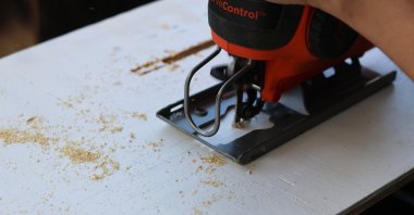 Felicia Fonseca uses a jigsaw to cut slits into a piece of plywood for a wedding sign at a do-it-yourself party at an apartment in Flagstaff, Ariz., U.S., Feb. 15, 2026. (AP Photo)