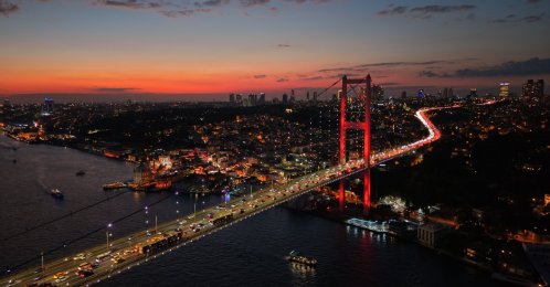 The Bosporus Bridge glows red at night as traffic flows beneath Istanbul’s skyline, Istanbul, Türkiye, Oct. 1, 2025. (Shutterstock Photo)