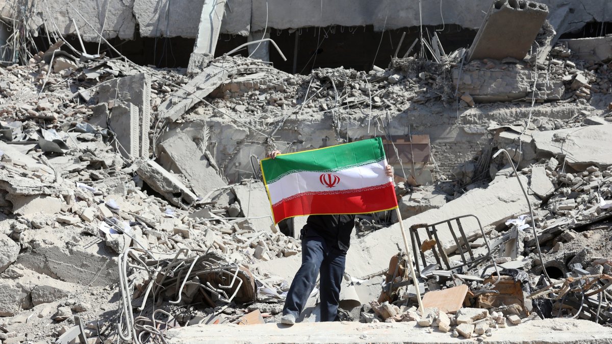 A man places Iran's national flag among the ruins of a damaged police station building in central Tehran, Iran, March 4, 2026. (EPA Photo)