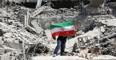 A man places Iran's national flag among the ruins of a damaged police station building in central Tehran, Iran, March 4, 2026. (EPA Photo)