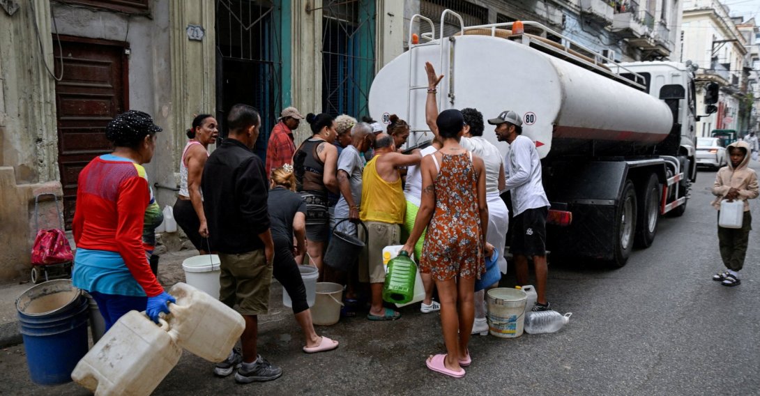 People gather around a water tanker truck to fill up buckets and other containers as severe fuel shortages have disrupted water pumping and distribution, in Havana, Cuba March 19, 2026. (Reuters Photo)