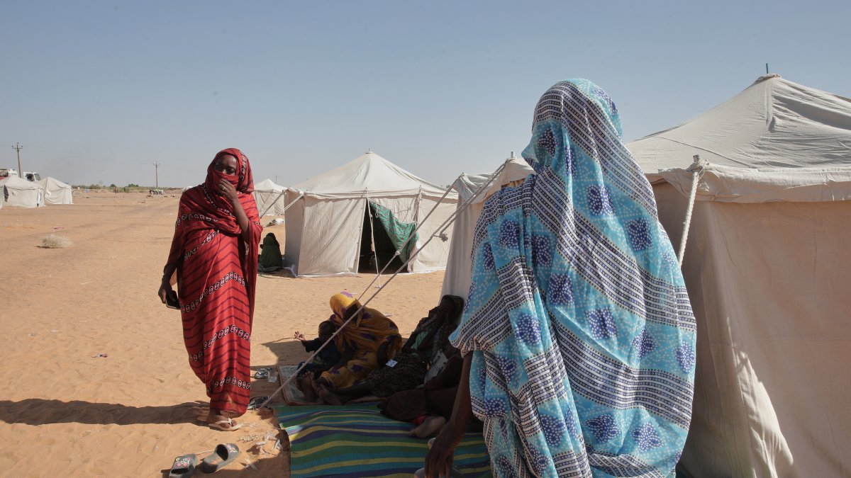Two women stand outside their tent at the newly established el-Afadh camp in al Dabbah, Sudan's northern state, Nov. 17, 2025. (AP Photo)
