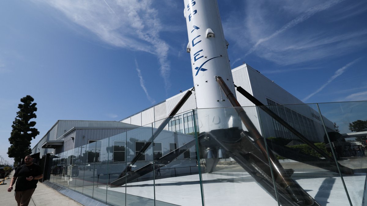 People walk past a SpaceX Falcon 9 rocket displayed outside the Space Exploration Technologies Corp. facility in Hawthorne, California, U.S., March 26, 2026. (AFP Photo)
