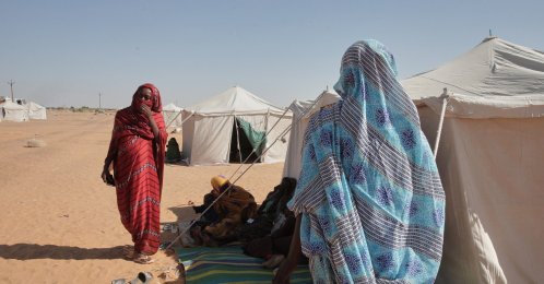 Two women stand outside their tent at the newly established el-Afadh camp in al Dabbah, Sudan's northern state, Nov. 17, 2025. (AP Photo)