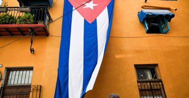A man walks past a Cuban flag hung on the facade of a house, Havana, Cuba, March 26, 2026. (AFP Photo)