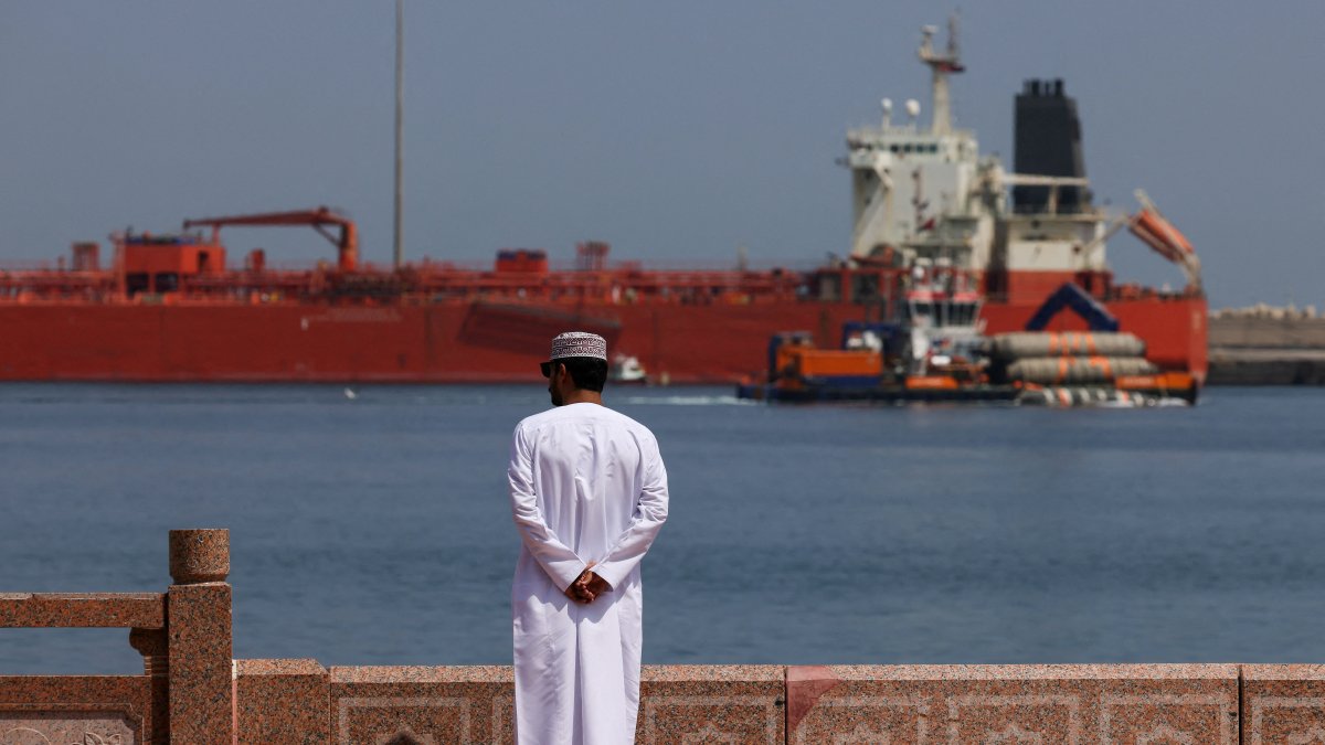 A man stands near the waterfront as a vessel sits at anchor, amid the U.S.-Israeli conflict with Iran, at Sultan Qaboos Port in Muscat, Oman, March 16, 2026. (Reuters Photo)
