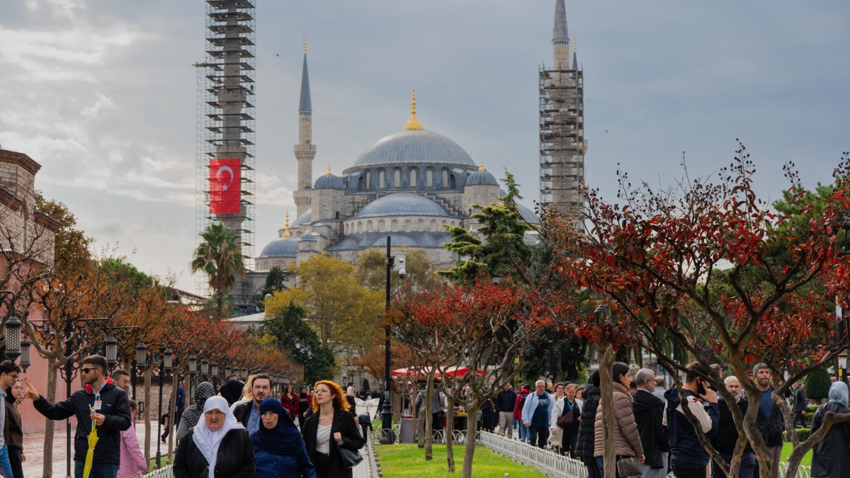 Visitors walking near the Blue Mosque in Istanbul during autumn, with colorful trees in the foreground and the historic domes and minarets rising behind, Istanbul, Türkiye, Oct. 25 2025. (Shutterstock Photo) 