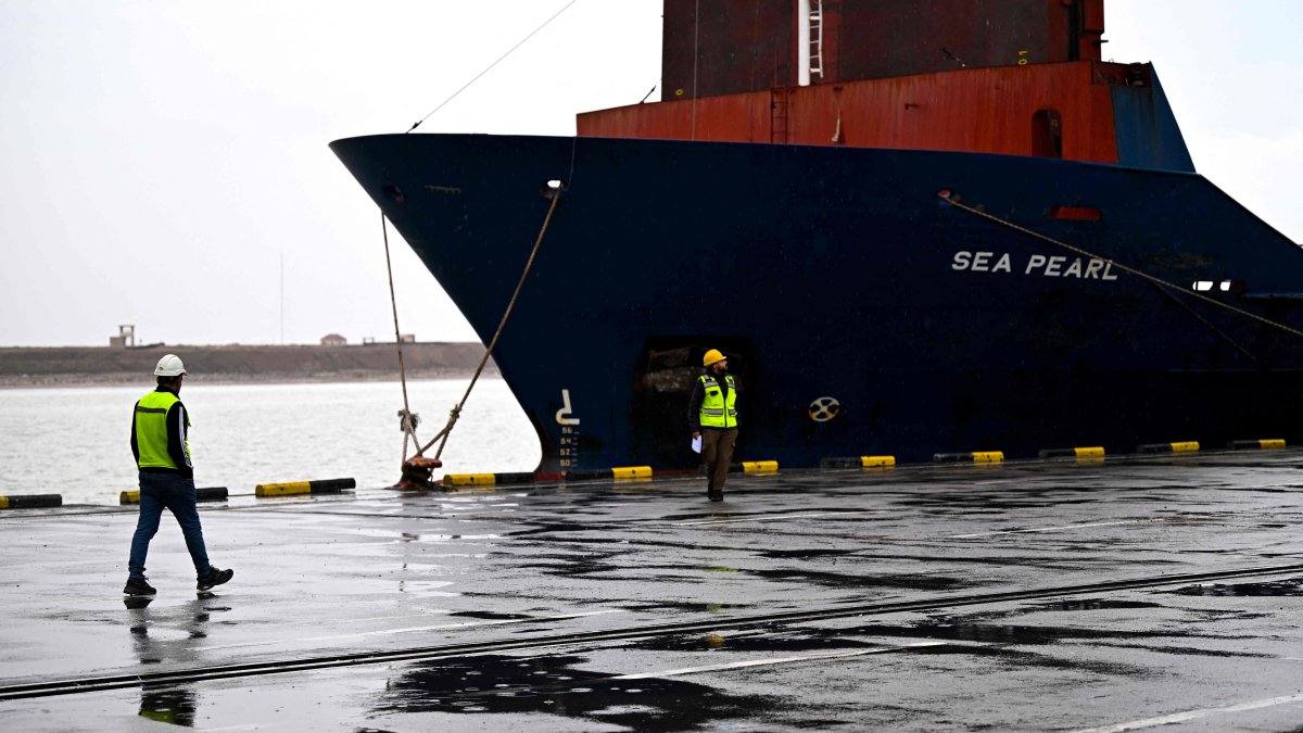 Dock workers walk past a container ship at the Port of Umm Qasr, Basra, Iraq, March 12, 2026. (AFP Photo)