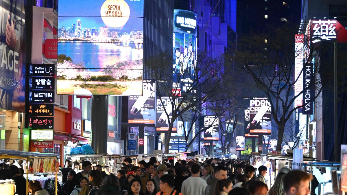 People walk beneath digital billboards in Myeongdong's shopping district, Seoul, South Korea, April 1, 2026.  (AFP Photo)