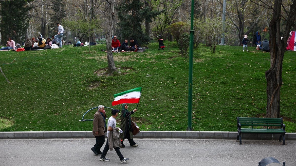 A woman waves an Iranian flag as she walks in a park on Nature Day, amid the U.S.-Israeli war on Iran, in Tehran, Iran, April 2, 2026. (Reuters Photo)