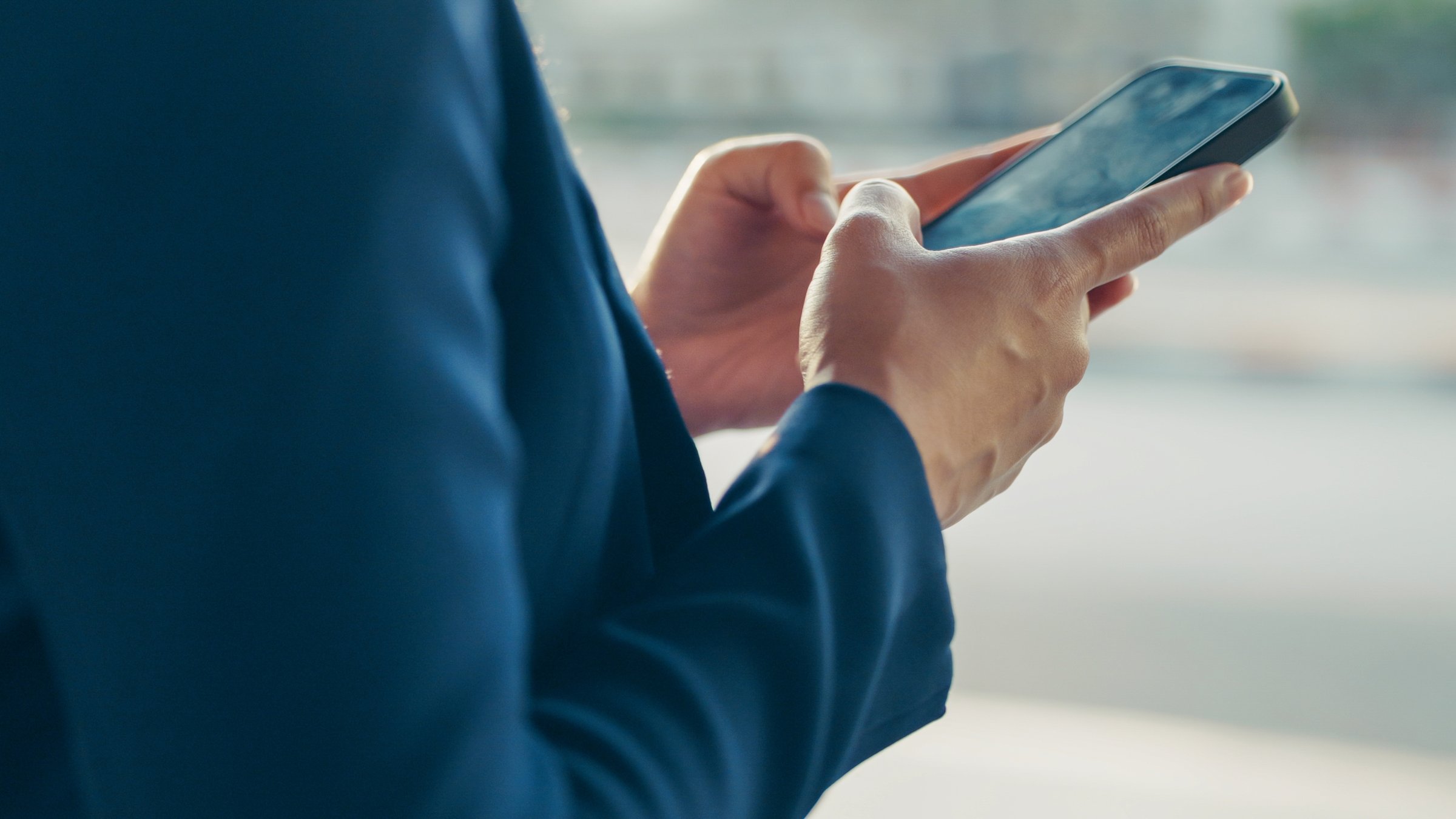 A man uses a smartphone outdoors. (Shuttersock Photo)