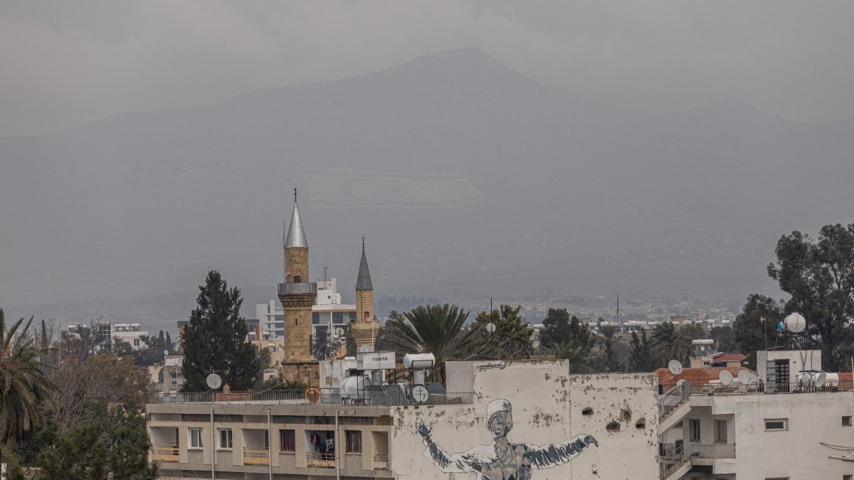 The flag of the Turkish Republic of Northern Cyprus is visible on Beşparmak (Pentadaktylos) mountain behind a mosque minaret in Lefkoşa, Feb. 12, 2024. (AFP File Photo)