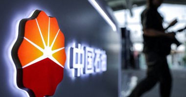A man walks next to a logo of the China National Petroleum Corporation (CNPC), Beijing, China, Sept. 11, 2025. (Reuters Photo)