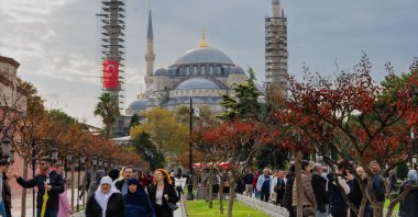 Visitors walking near the Blue Mosque in Istanbul during autumn, with colorful trees in the foreground and the historic domes and minarets rising behind, Istanbul, Türkiye, Oct. 25 2025. (Shutterstock Photo) 