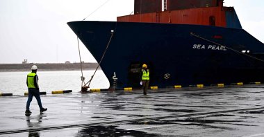Dock workers walk past a container ship at the Port of Umm Qasr, Basra, Iraq, March 12, 2026. (AFP Photo)