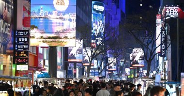 People walk beneath digital billboards in Myeongdong's shopping district, Seoul, South Korea, April 1, 2026.  (AFP Photo)