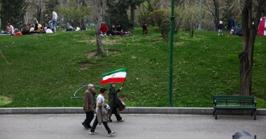 A woman waves an Iranian flag as she walks in a park on Nature Day, amid the U.S.-Israeli war on Iran, in Tehran, Iran, April 2, 2026. (Reuters Photo)
