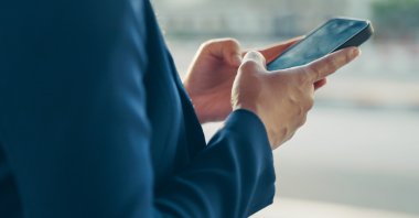A man uses a smartphone outdoors. (Shuttersock Photo)